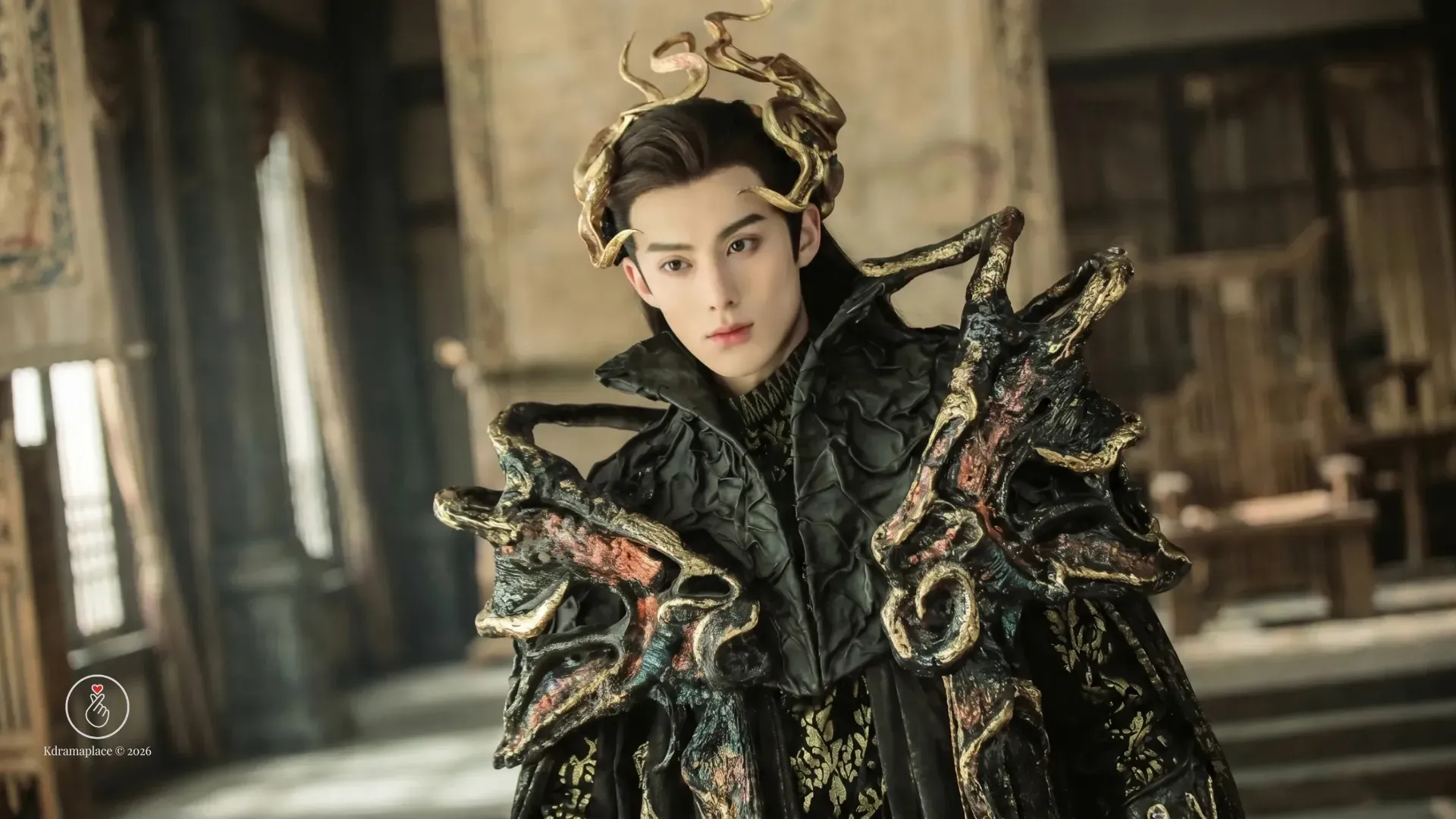 Ator chinês Dylan Wang caracterizado com armadura preta imponente e coroa dourada de chifres em plano médio.